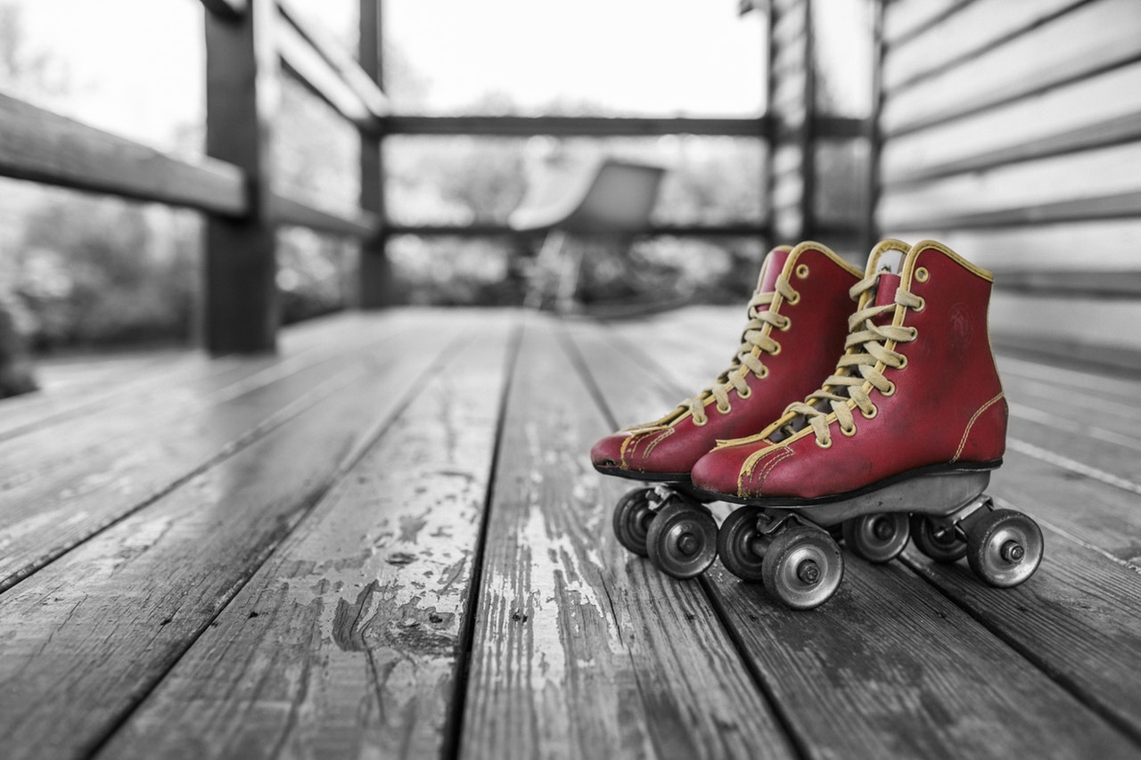 Red vintage roller blades on a porch, against a black and white background.