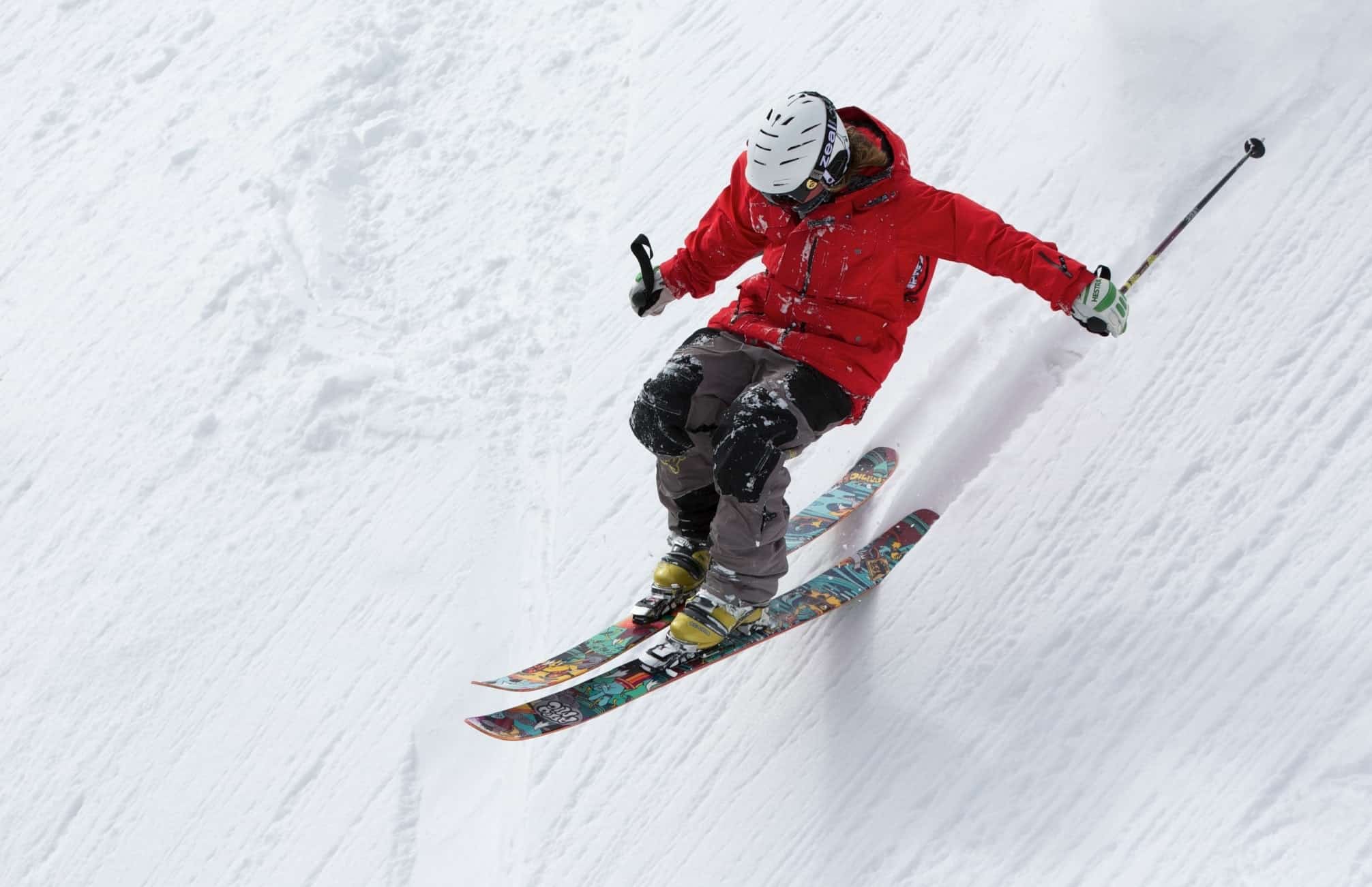 Skier in red, skiing down steep slope