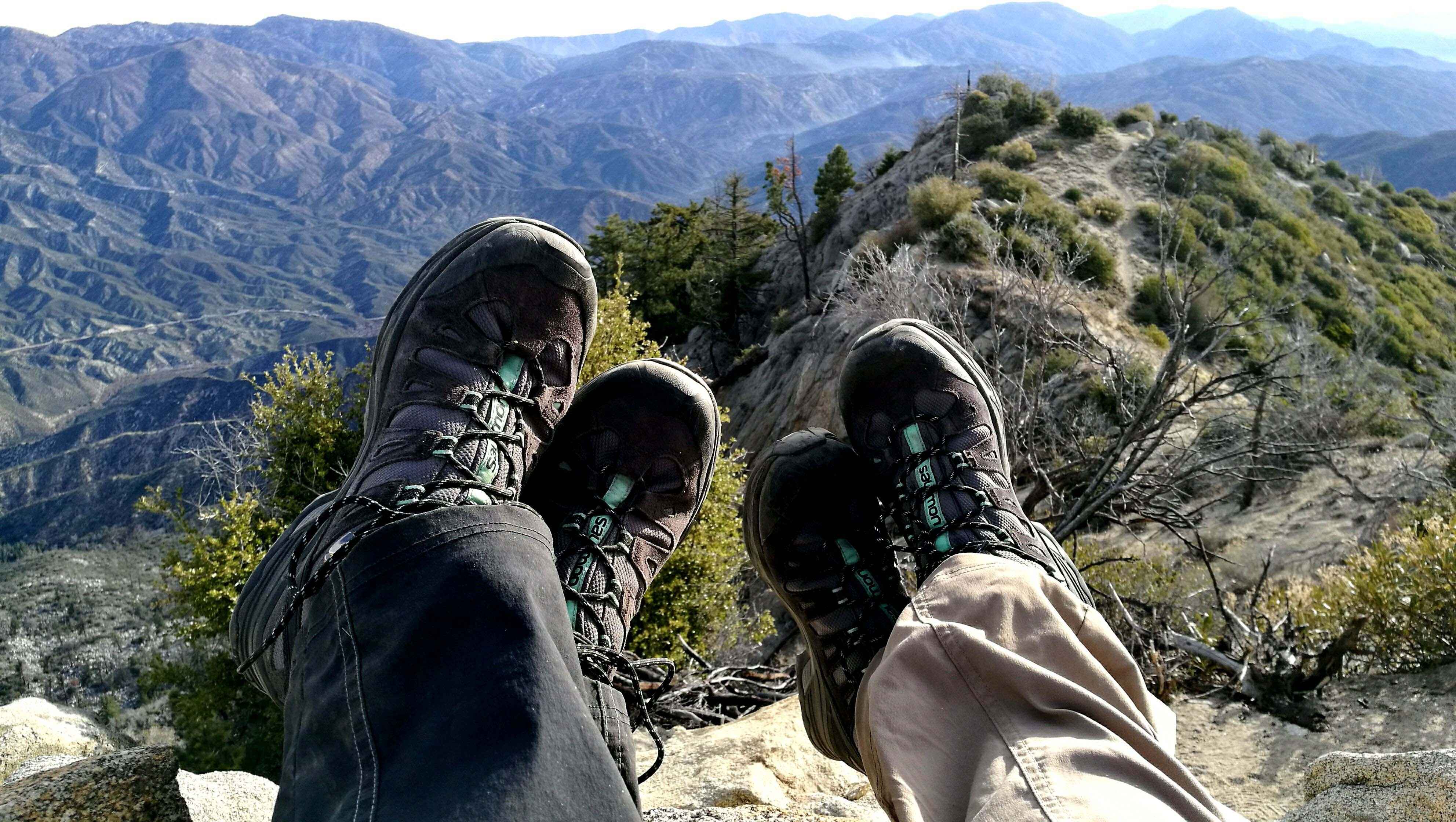 Two pairs of feet in hiking boots at the top of a mountain