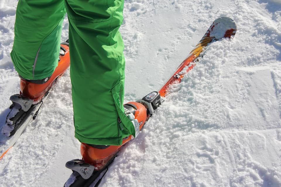 Close up of person wearing pair of skis in snow